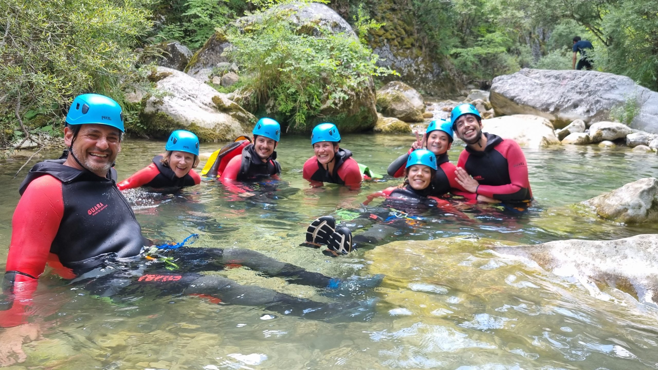Des collaborateurs souriants et complices se détendent ensemble dans l'eau d'une vasque naturelle lors d'une activité de team building en canyoning.